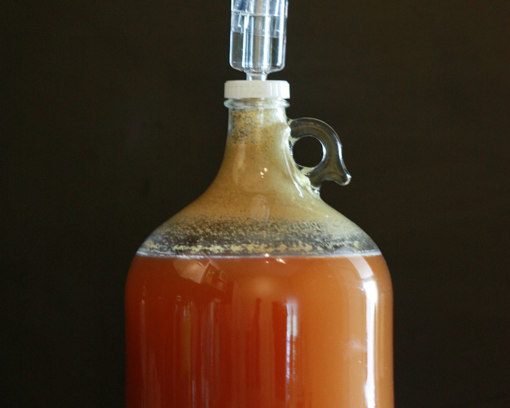 Glass jug of cider on a porch rail